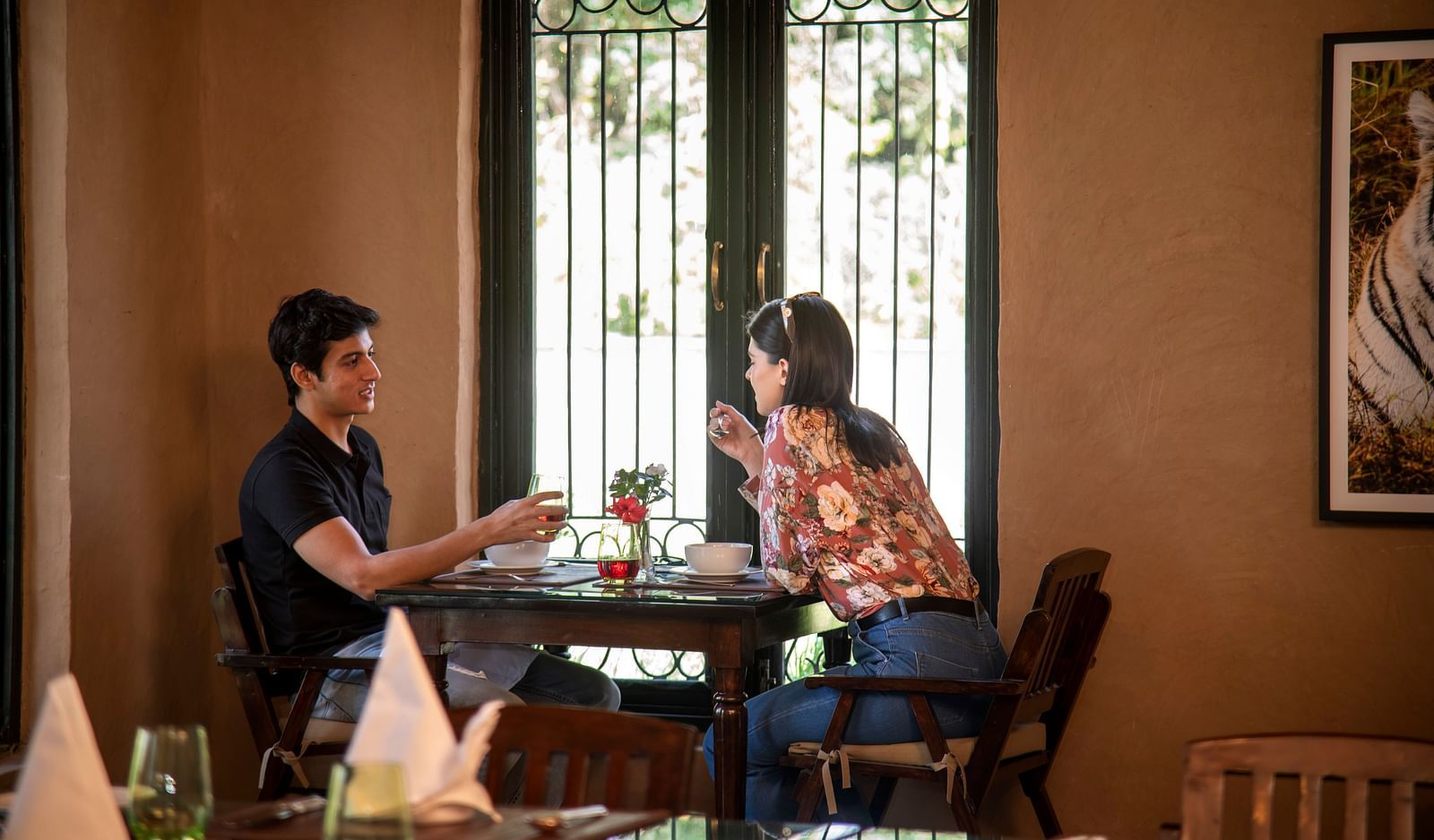 A couple enjoying a breakfast by the window at our restaurant near Haridwar - Aalia Jungle Resort & Spa