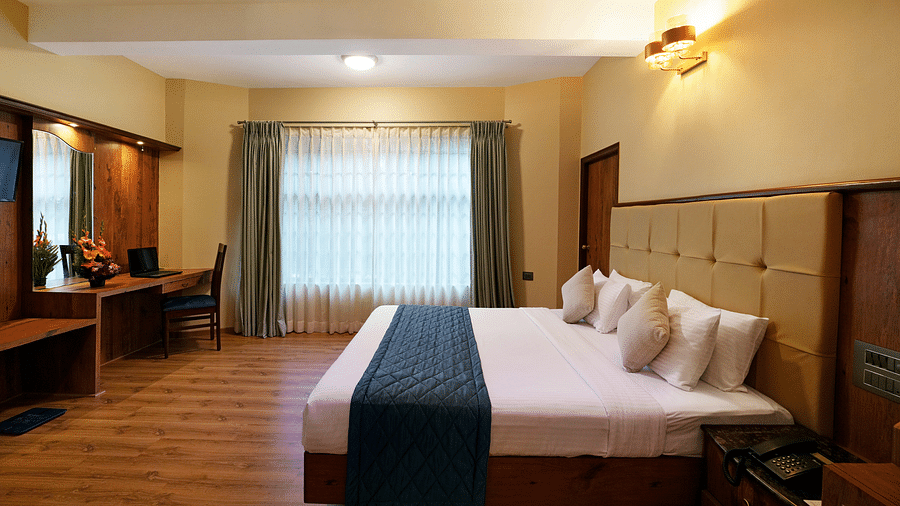 An Executive Room with a large bed, wooden decor, and natural light - Cross Roads Inn, Bengaluru