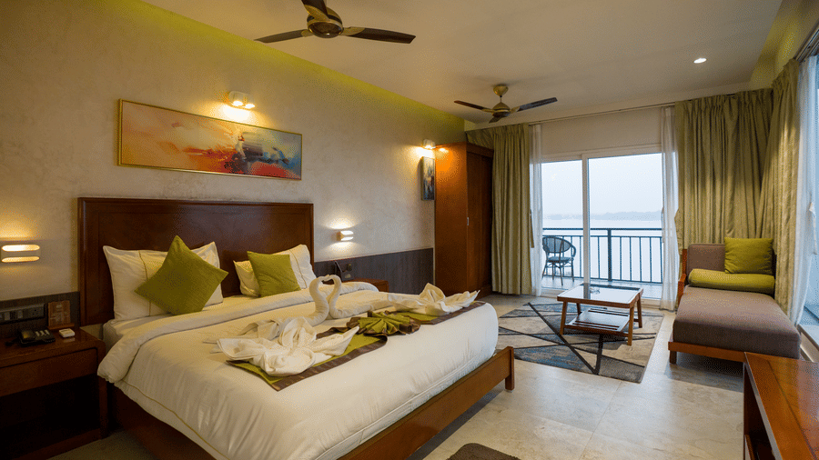 Superior Room with double bed, green accents, and balcony door at Hotel Sonar Bangla, Taki.