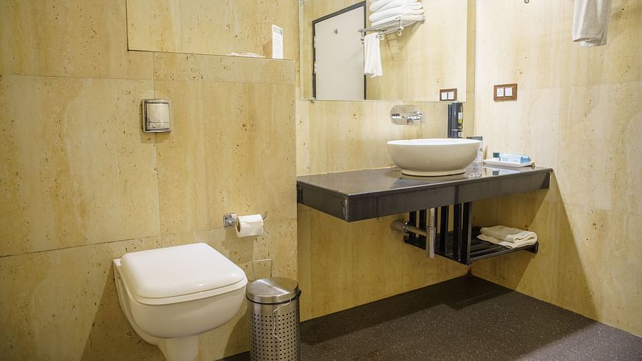 A modern bathroom at Orsino Spa Resort with a toilet, a basin set into a vanity, and light-coloured tiled walls.