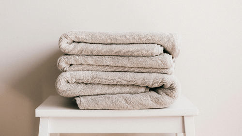 a few white coloured towels neatly folded and kept on a stool