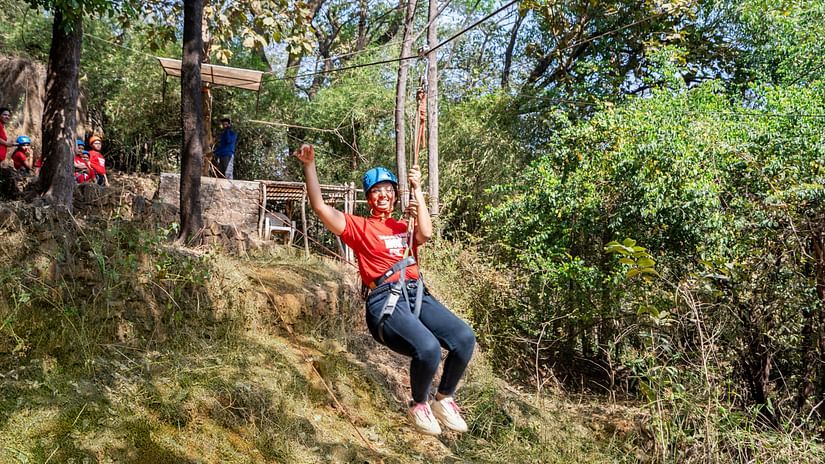 Individual sliding down a zipline in a wooded adventure area at Nature Trails Durshet.
