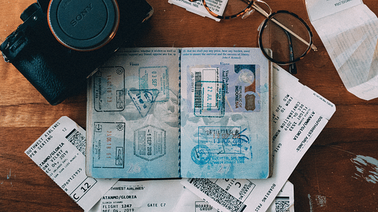 An open passport along with a camera glasses and other papers