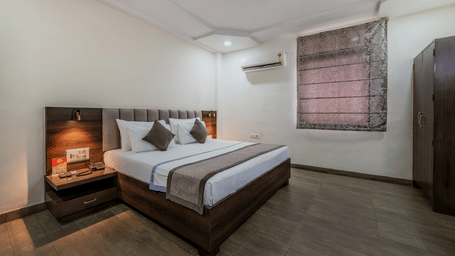King Standard Room with a dark wooden headboard, air conditioning, and a wooden wardrobe at Hotel Highway King, Shahpura, comfortable.