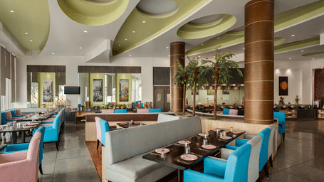 The indoor dining area of Jalpaan coffee shop at Ramada by Wyndham Bodh Gaya Mahabodhi features neatly arranged tables and comfortable booths.