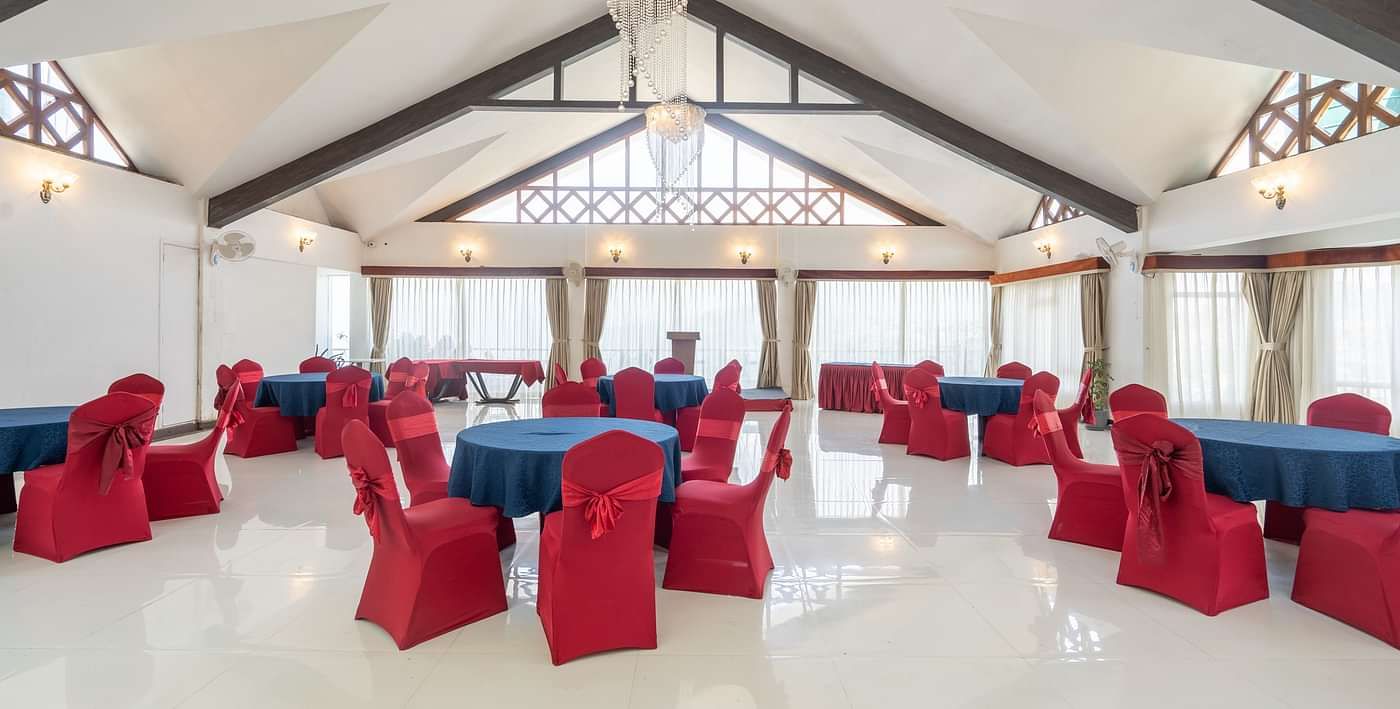 A shot of an expansive banquet hall with a seating arrangement featuring red and blue chairs and tables.