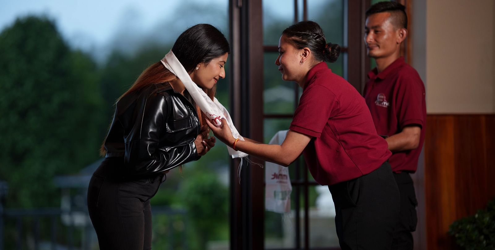 A hotel staff member in a uniform is assisting a guest, possibly with check-in or service, demonstrating the hospitality at Summit Enigma Resort and Spa.