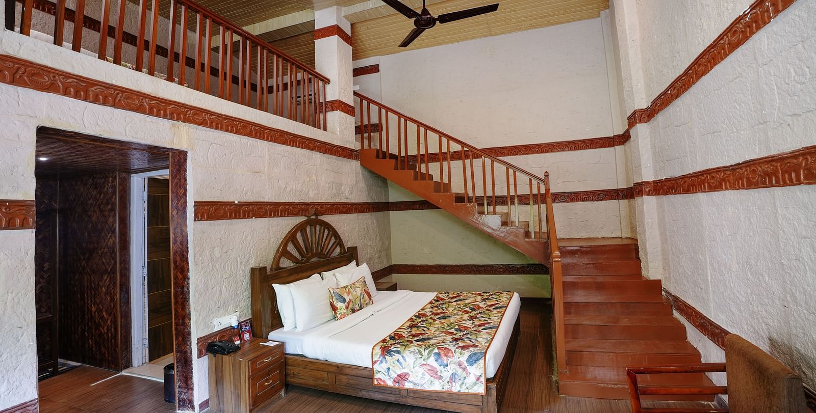 Duplex ethnic villa featuring a spacious bedroom and staircase leading to an additional room at Summit Green Lake Tea Resort & Spa, Kaziranga