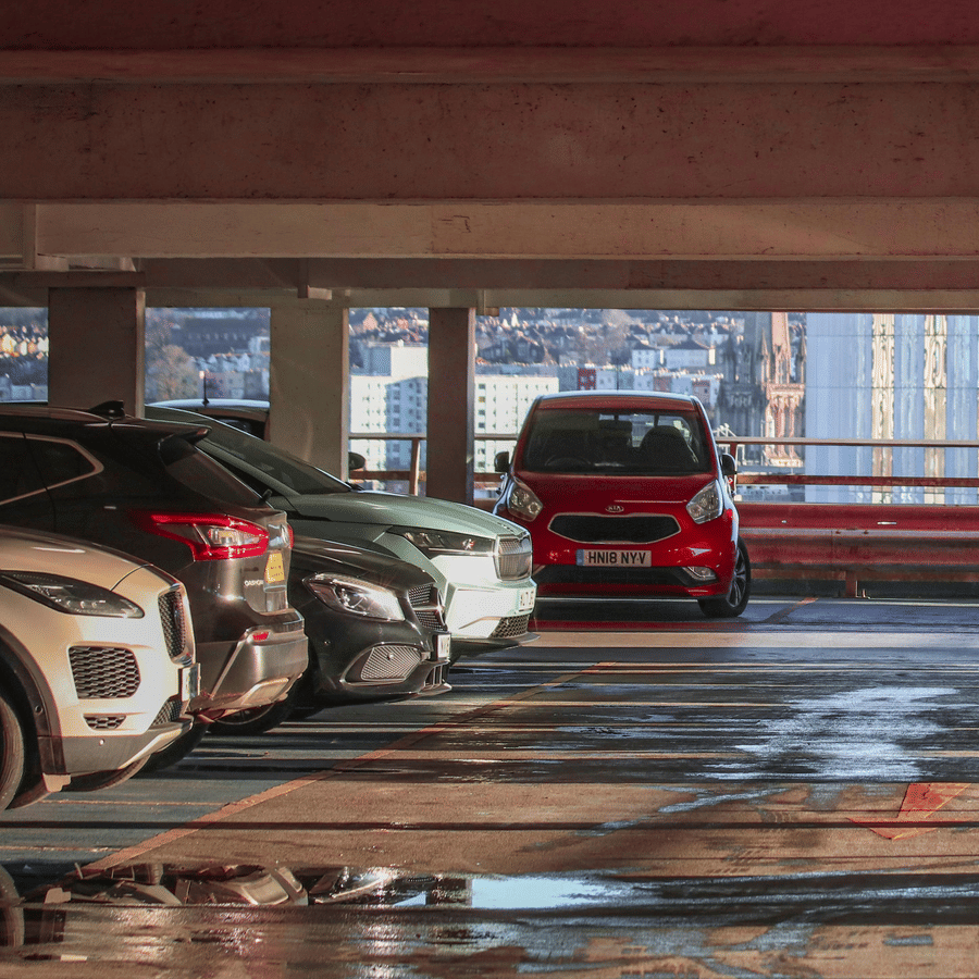 Covered parking area with multiple cars parked in designated spaces inside a multi-level parking garage.