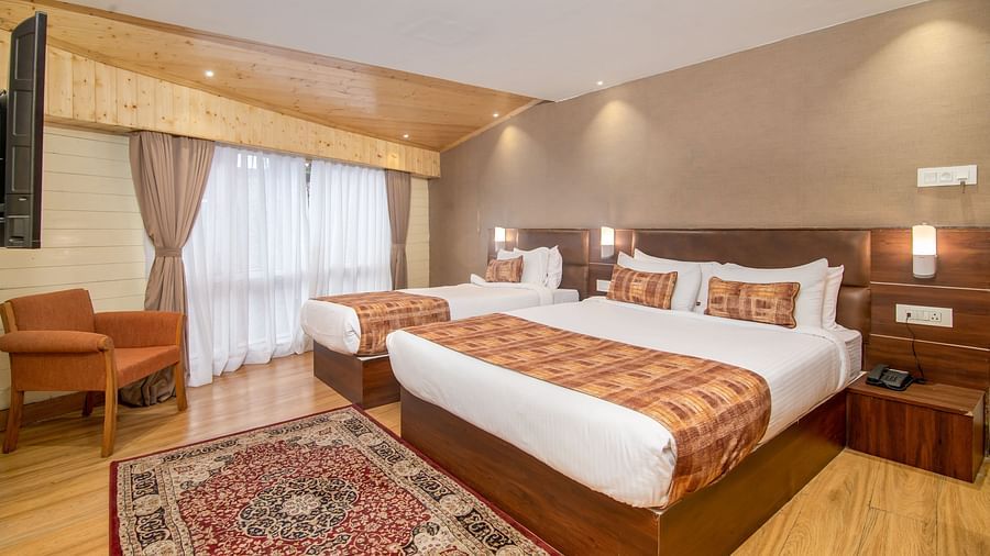 Side view of a large double bed and a single bed in the Triple Deluxe Room at Hotel Sumitel Vista T.V Tower 1