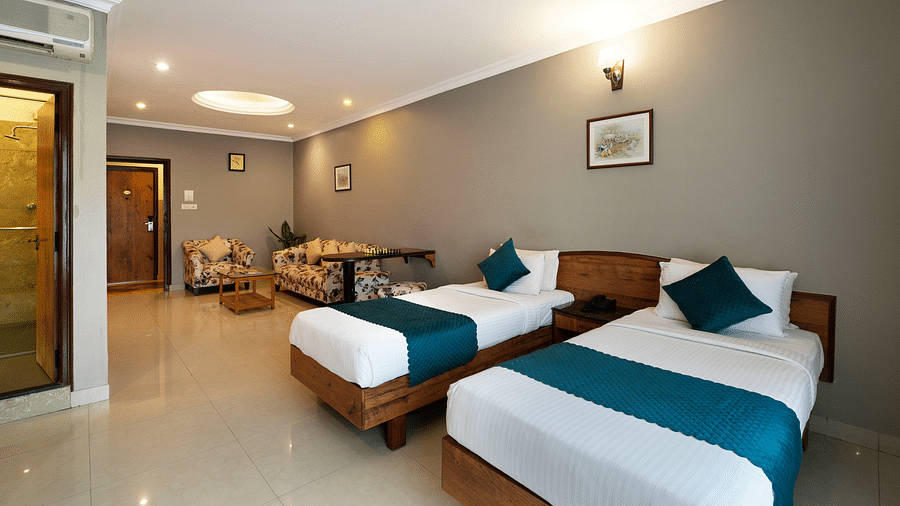 An image of an elegant Executive Room featuring twin beds and a seating area - Cross Roads Inn, Bengaluru