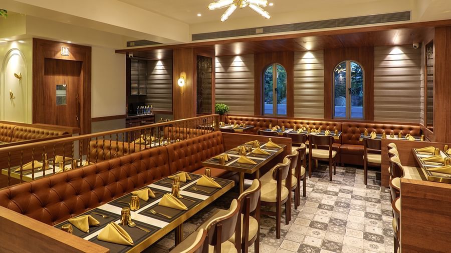 A warmly lit restaurant area features multiple tables set for dining, wooden accents, and decorative wall panels - Melior Inn