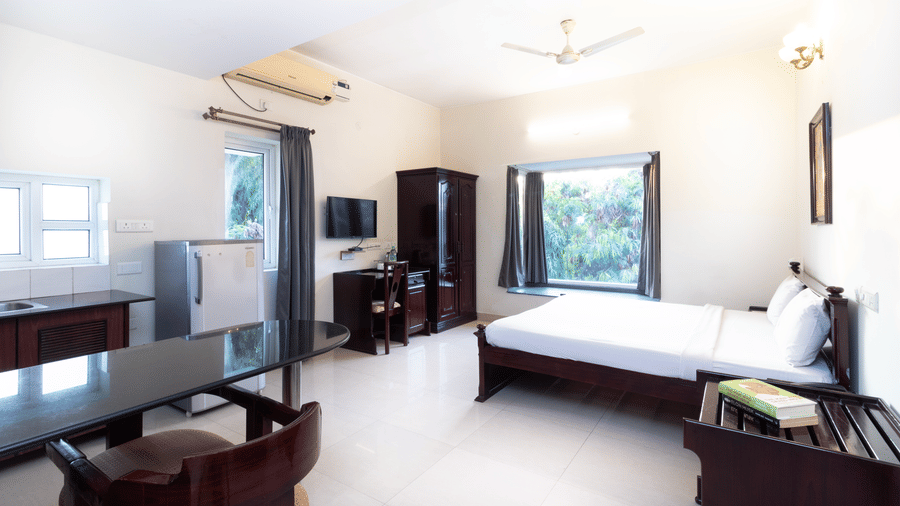 Hotel room with a double bed, an air conditioner, and grey curtains at Sanctum Suites Indiranagar, Bangalore.