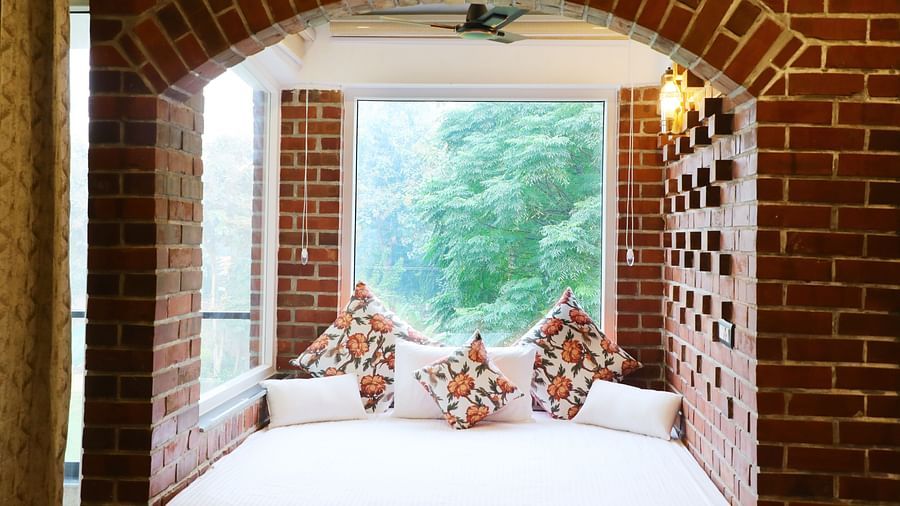 A  bay window bed overlooking lush greenery, offering a view at Tisya Farms, Gurgaon.