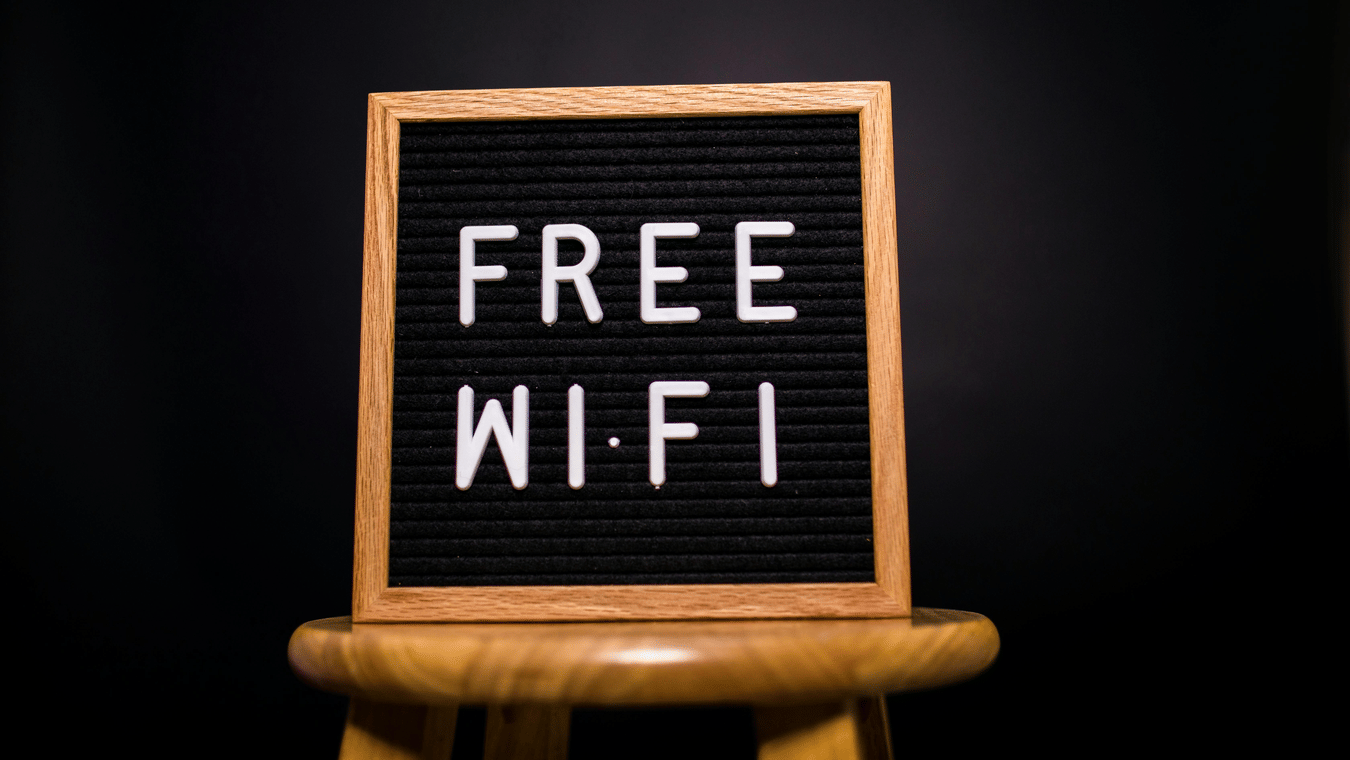 A black felt letter board with the words 'FREE WI-FI' in white letters, sitting on a wooden stool.