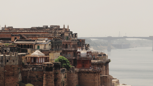Ramnagar Fort, Varanasi, featuring its layered architecture and a river scene with a bridge in the background.