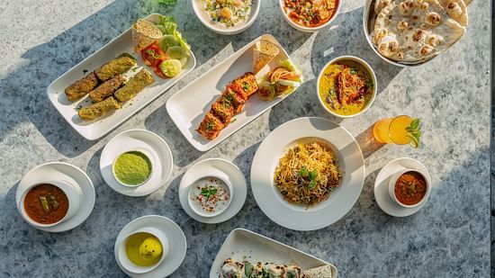 Overhead spread of Indian dishes including naan, curry bowls, rice and chutneys arranged on a stone tabletop at Clarks Inn Suites, Hyderabad