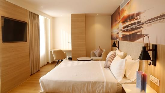 A well-designed suite in Zirakpur featuring a comfortable bed and seating area - Tulip Inn, Zirakpur