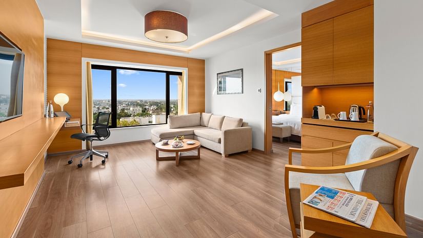 Club Suite room with a cozy sofa, chair in the corner, and a city view from the window at The Residency Towers Coimbatore.