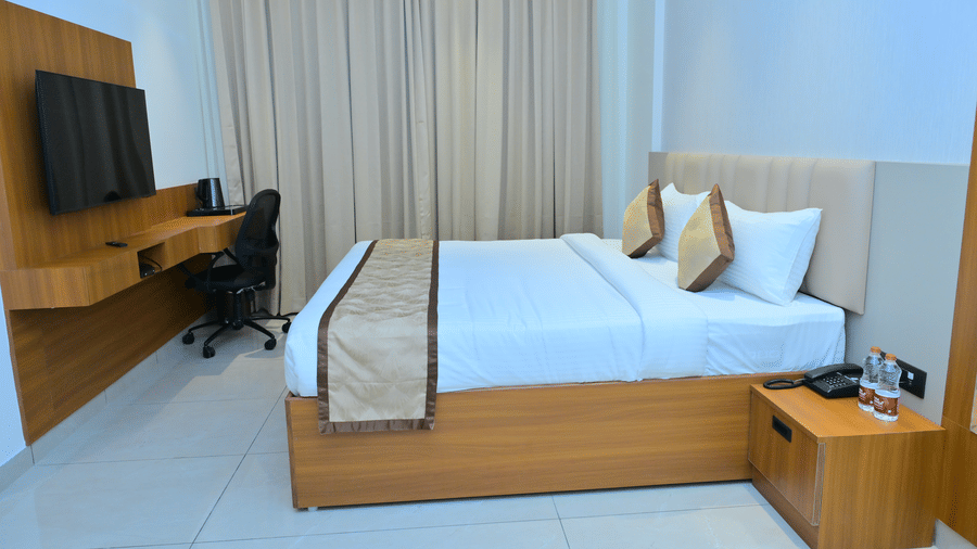 Bedroom of Bhavanis Vista By Icon featuring a bed, a headboard, a television, and a desk.