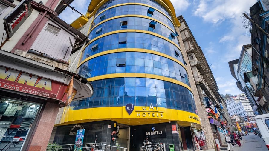 The bright yellow and blue glass exterior of the Yashshree Jai Hotel & Banquet, Darjeeling building.