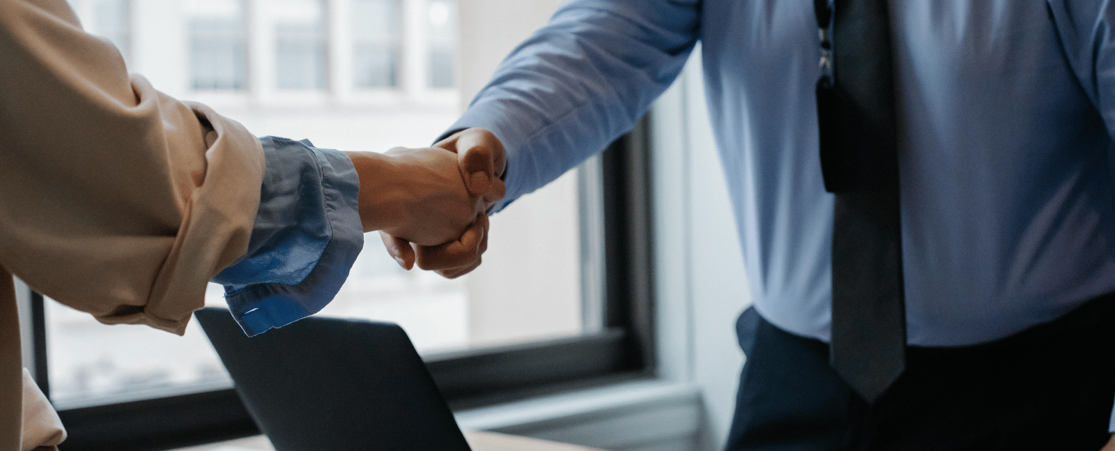 A woman shaking hands with a man dressed in business formals.