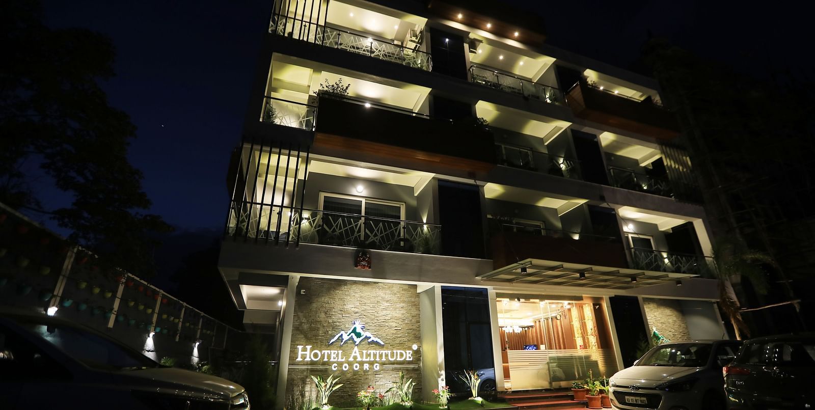 Facade of Hotel Altitude at night with cars parked in front of it.