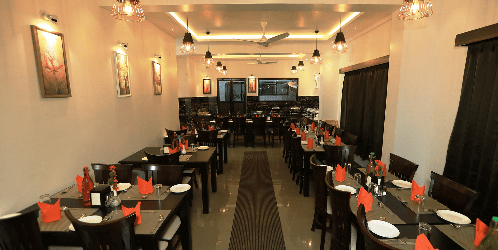 A dining space with tables and chairs and lights on the ceiling at Hotel Altitude, Madikeri.