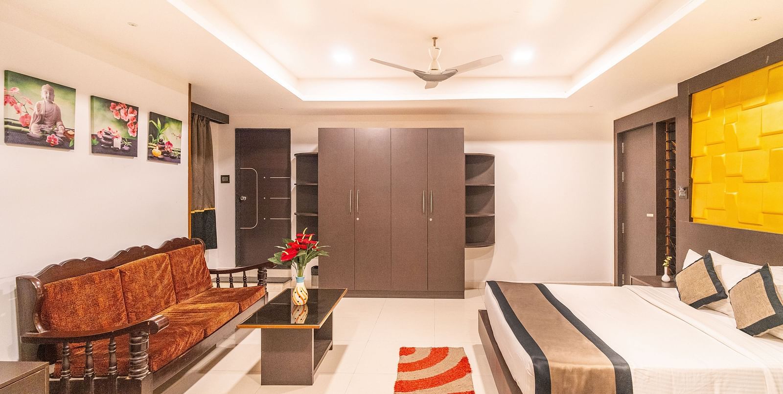 A room with a bed and a sofa in front of it at Parampara Residency, Kushalnagar.