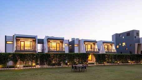 Facade view of DLS Forest Vines Resort, illuminated by warm lights from the windows and doors.