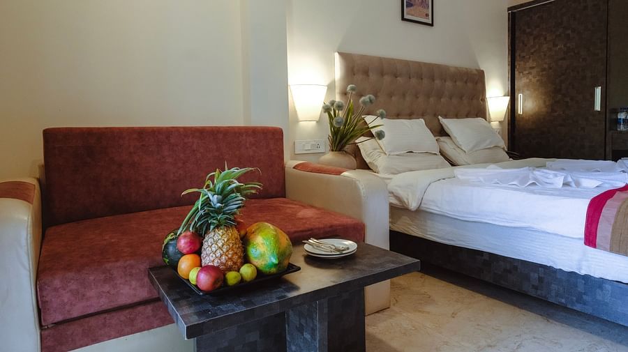 A cosy bedroom with a bed, a red sofa, and a fresh fruit platter on the table – The Verda de Miranda Resort.