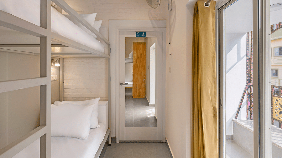 A front angle view of the dorms at Bedzzz in Varanasi showcases large windows adorned with curtains, inviting natural light into the space. The design combines comfort and functionality, creating a welcoming atmosphere for guests.