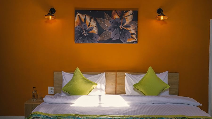A spacious bed with a neatly set blanket and pillows, a photo frame above the headboard, and night lamps on both sides at BluSalzz Villas - The Green Roof, Bhimtal.