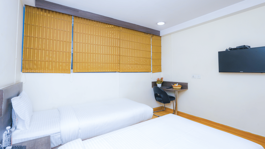 A contemporary hotel room with a large bed, television, and wooden blinds on the window - Hyphen Business Hotel, Noida