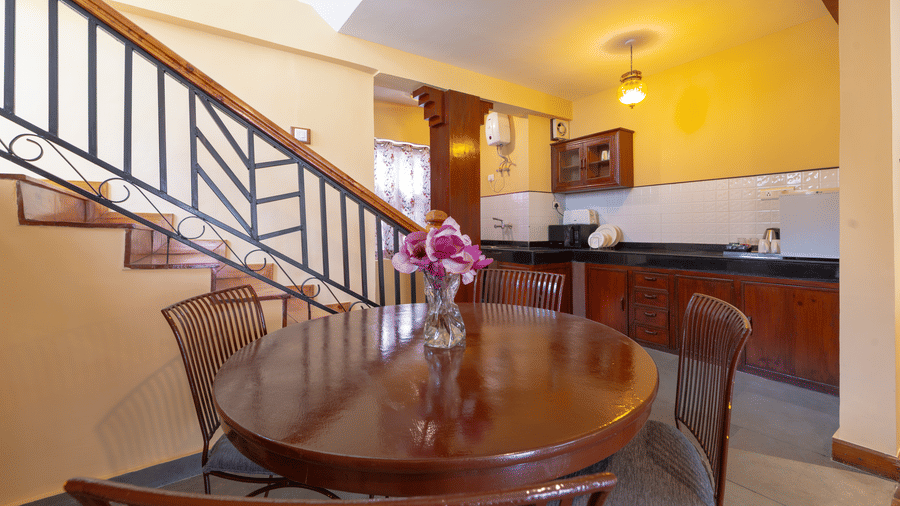 An intimate dining area with a round wooden table and chairs located next to an indoor staircase - Johnson Lodge & Spa, Manali