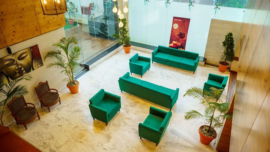 A bird's eye view of a large, open lobby area at Orsino Spa Resort with sofas and armchairs arranged on a light-coloured floor, with plants for decoration.