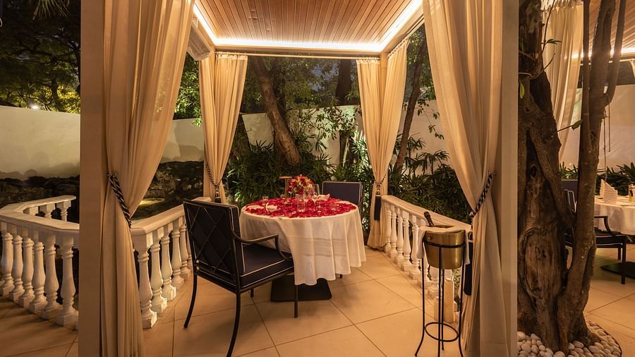 A charming gazebo-style setup with ambient lighting, elegant drapery, and greenery around