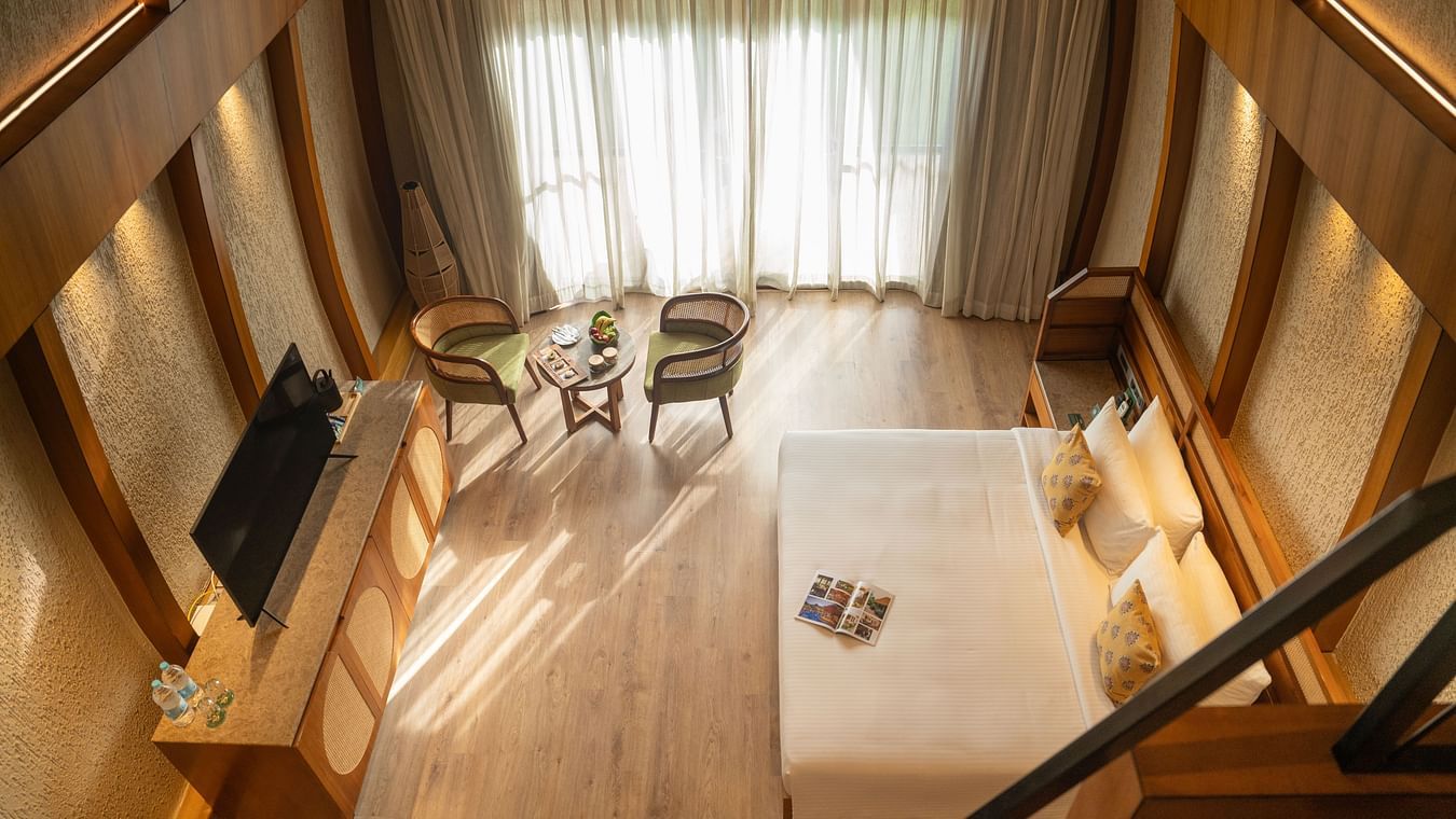 A stunning kind size bedroom with high ceilings, seating area, and large windows allowing natural light at Ananta Spa and Resort, Ajabgarh.