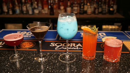 Three colorful cocktails placed on a bar counter at Park Plaza Ludhiana with a backlit liquor shelf and Sooraj branding visible in the background.