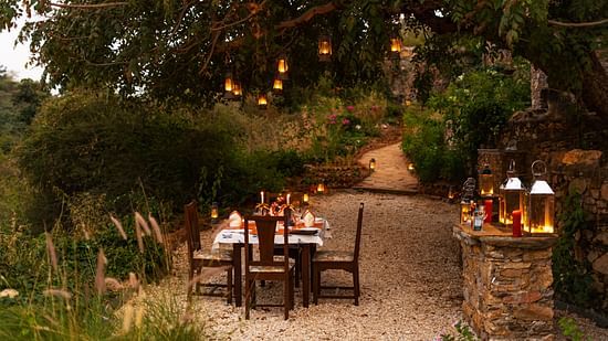 a table for four set up next on a pathway with forest cover surrounding it - Chunda Shikar Oudi, Udaipur