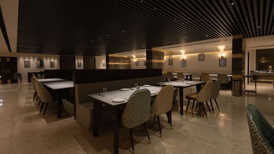 A spacious dining area at Pride Resort, Jodhpur, with tables and chairs arranged under warm, ambient lighting.