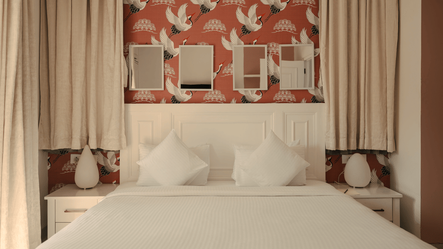 Elegant bedroom with red accent wallpaper and twin mirrors at Three BHK Premium Villa, Richmonde Ananta Elite, Goa.