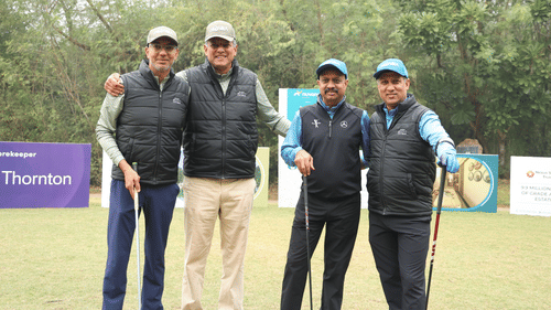 Four people standing together surrounded by lush greenery.- Heritage Village Resorts & Spa