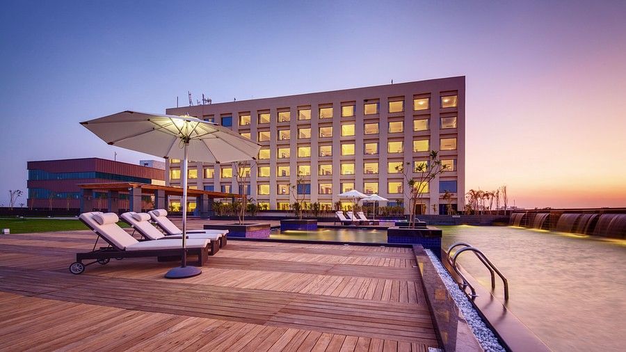 A hotel with a poolside area featuring lounge chairs, umbrellas, and a scenic sunset backdrop - Balaji Sarovar Premiere, Solapur