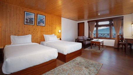 Twin bed resort room featuring full wood panelling on the walls and ceiling, with a cosy seating area by the window - Rungkhung Village Resort - The Signature Collection