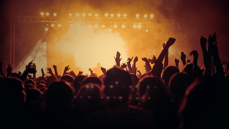 people with their hands raised in the air at a concert at night