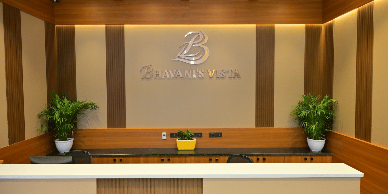 Reception desk of Bhavanis Vista By Icon featuring a counter, signage, and potted plants.
