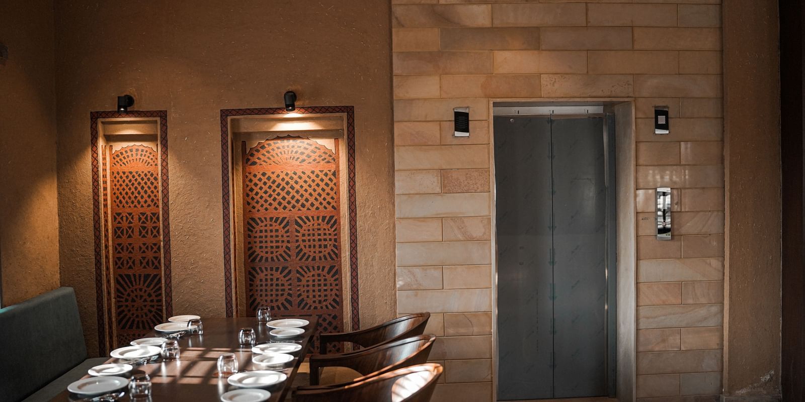 A restaurant dining area with tables and an elevator in the background at Aamaghati Wildlife Resort.