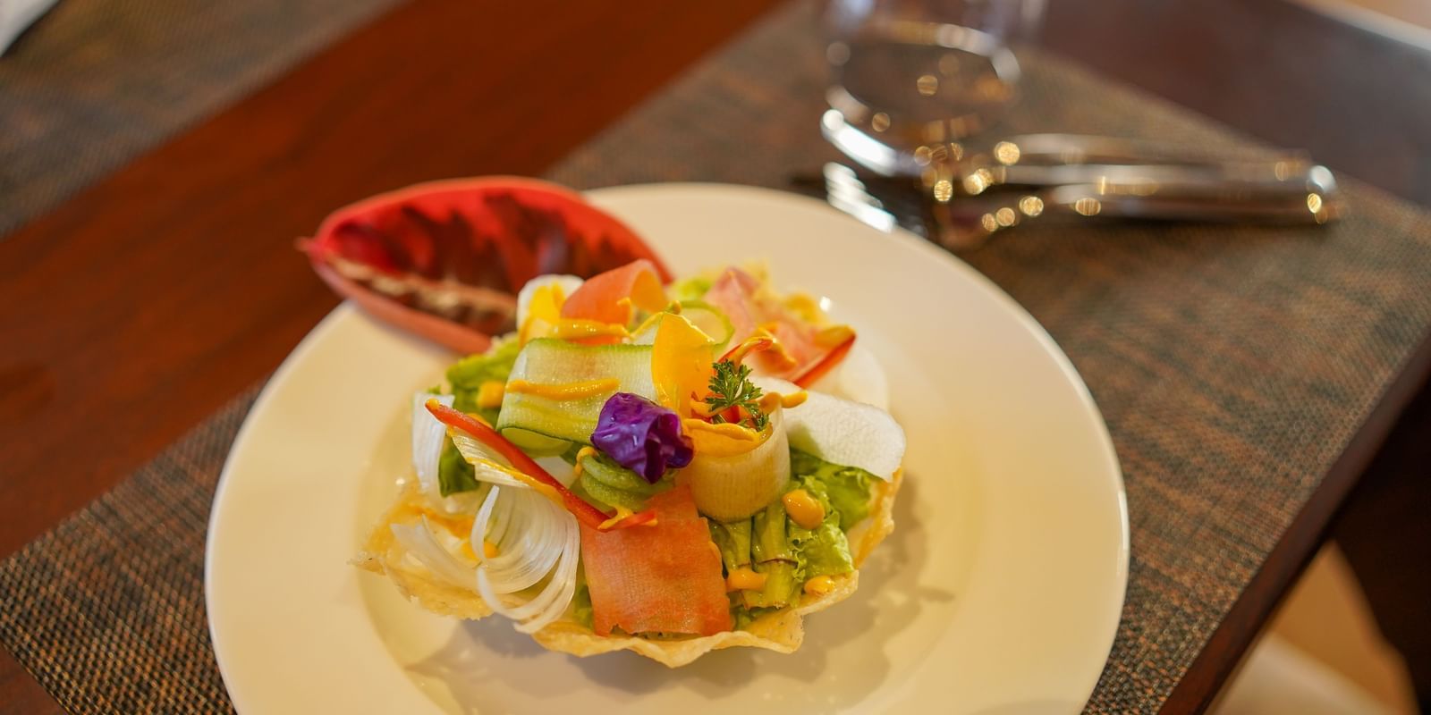A fresh and colourful salad, beautifully arranged on a plate at Aamaghati Wildlife Resort.