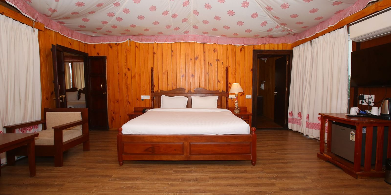 Spacious Luxury Wooden Tent with a king-sized bed and a corner cupboard at Aanandam Resort & Spa